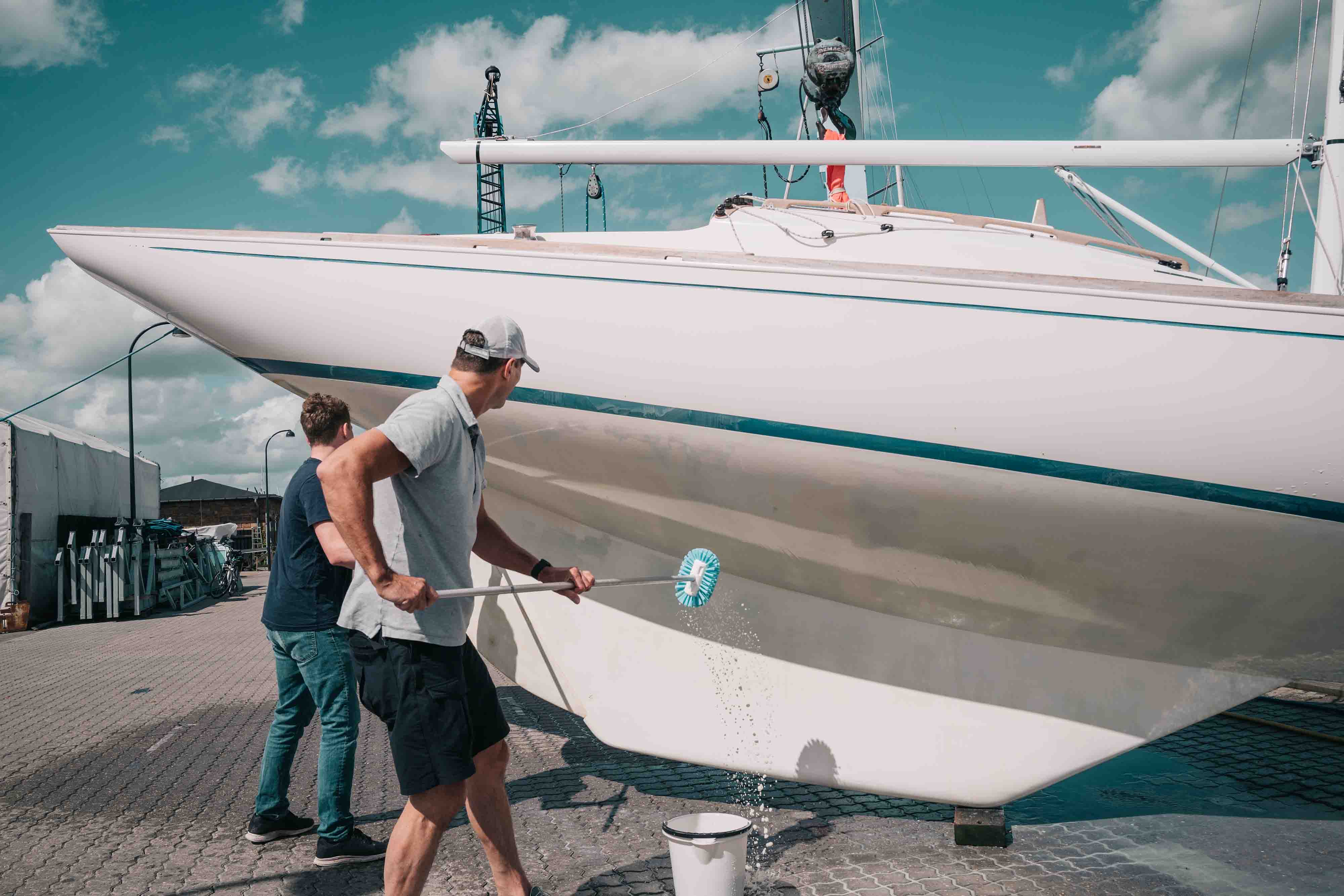Father and son cleaning a sail boat together on a sunny day before they head out to sea